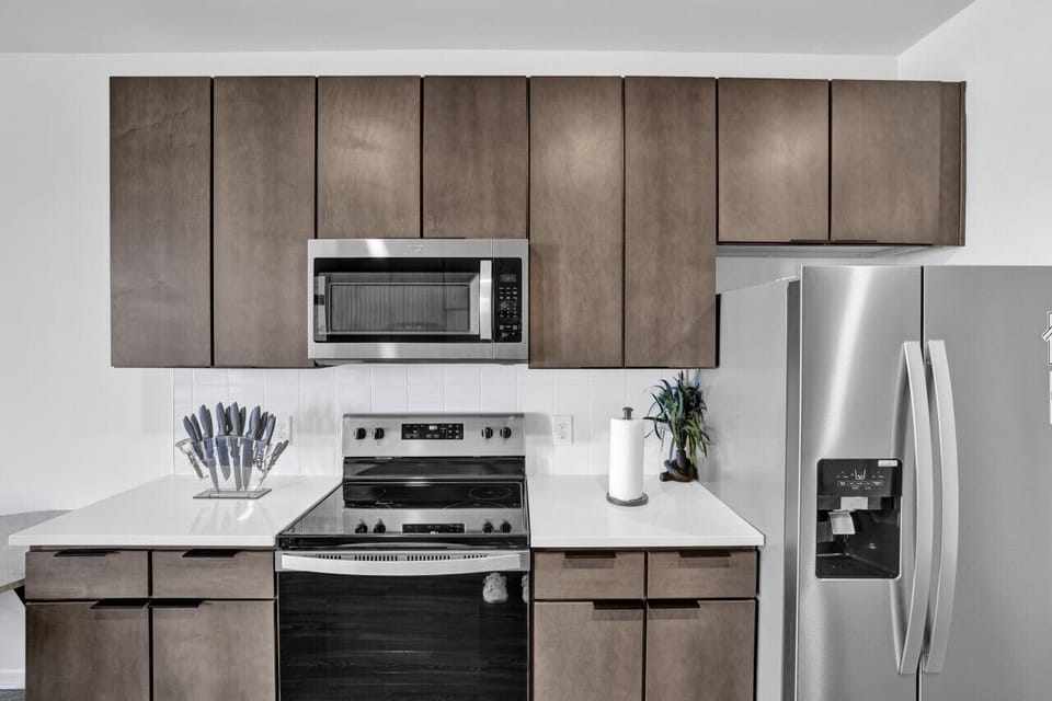 Modern kitchen with sleek stainless steel appliances and neatly arranged utensils, perfect for effortless cooking during your short-term rental stay.