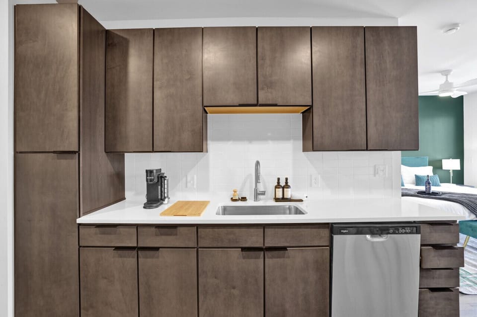 Bright white countertops in this furnished apartment complement sleek cabinetry, providing an aesthetic that is both contemporary and practical.