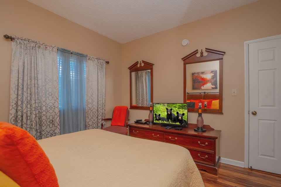 Slip into your cozy bedroom with warm wood furnishings, soft bedding, and natural light filtering through patterned curtains. Your private retreat awaits with entertainment and storage for all your vacation essentials.