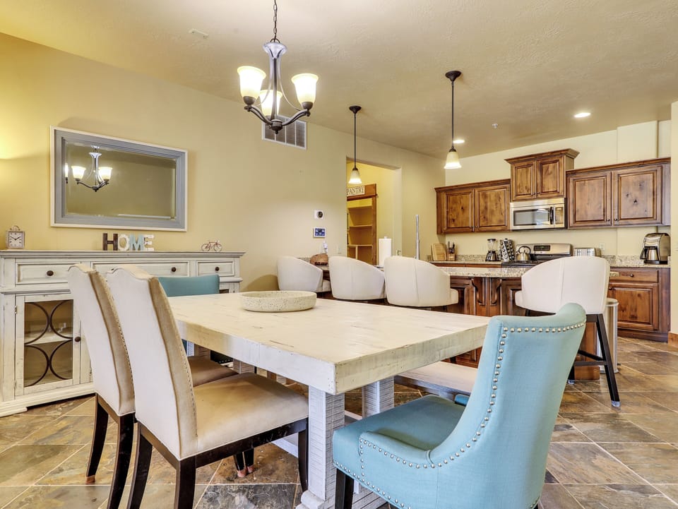 View of Dining Room with Dining Table & Chairs, Buffet Table, Chandelier, Pendant Lights, Kitchen Island with Seating for 4