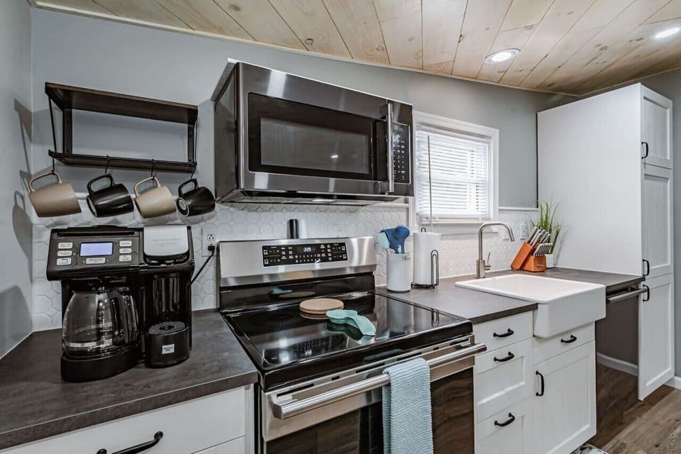 Cook and entertain with ease in the fully equipped kitchen, featuring a coffee station with Keurig and drip options, modern appliances, a farmhouse sink, and a charming dining area with bench seating.