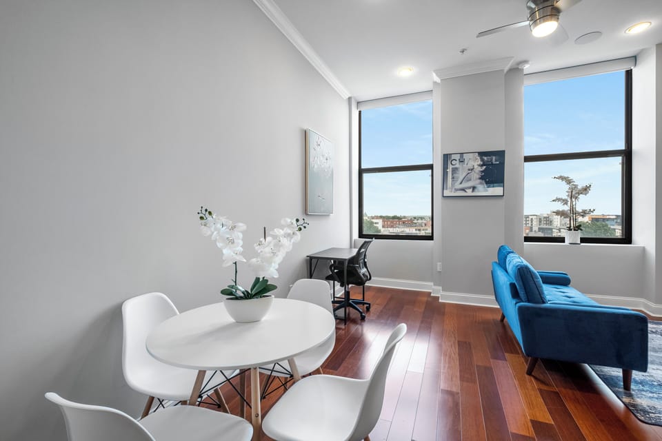 Dining area with round white table and contemporary chairs where you can enjoy meals with city views. 