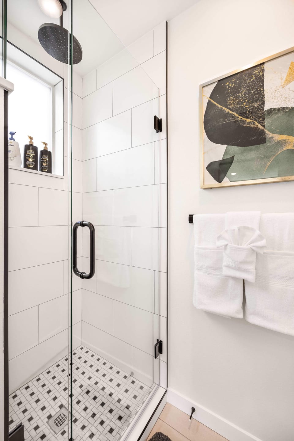 Indulge in a rejuvenating shower with our rainfall showerhead, surrounded by elegant tiling and modern black hardware