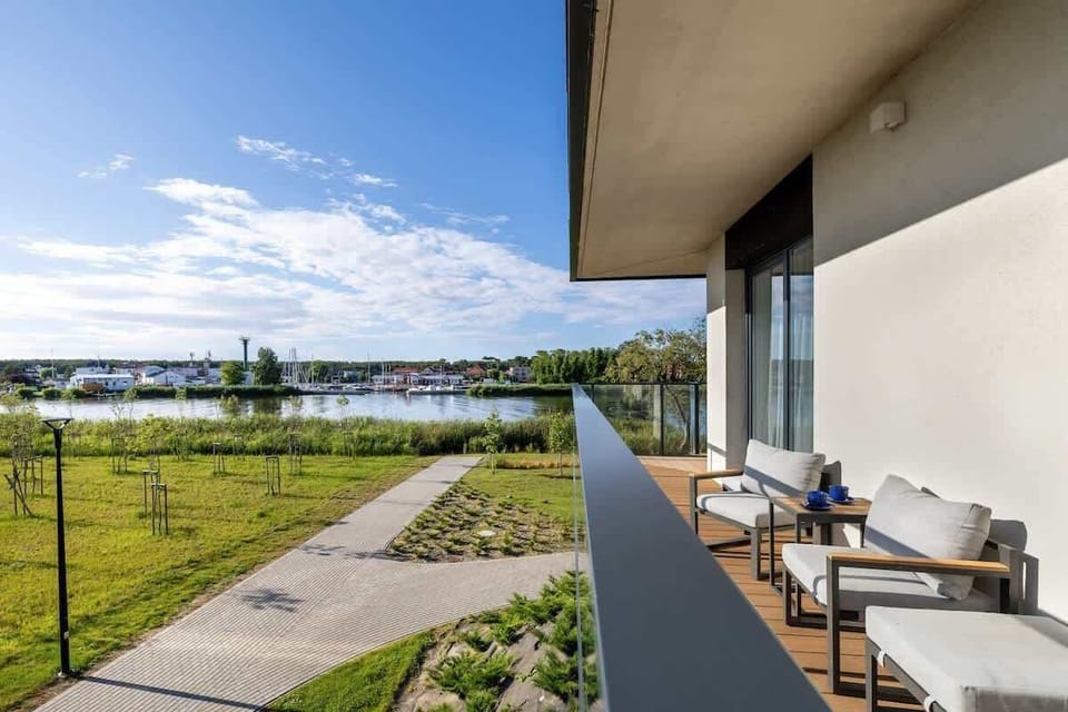 A balcony overlooking greenery and pathways, furnished with comfortable outdoor seating, invites open-air relaxation.