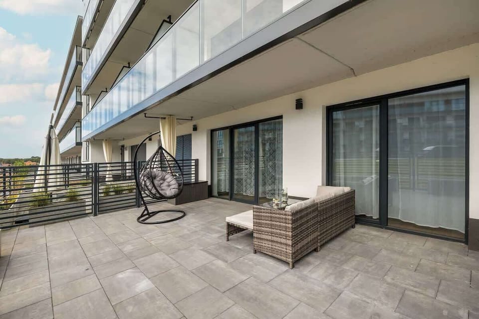 The spa area with a hot tub and mosaic tiles, surrounded by large windows overlooking greenery, offers luxurious relaxation.