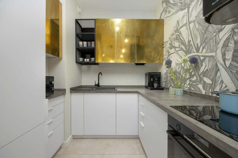 A stylish kitchenette with glossy fronts, decorative wallpaper, and modern appliances is fully equipped.
