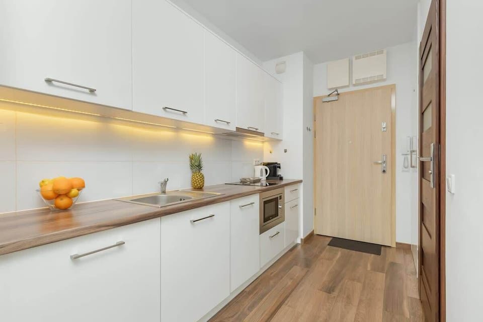 A modern kitchenette with a wooden countertop, white cabinets, and LED lighting creates a functional and stylish space.