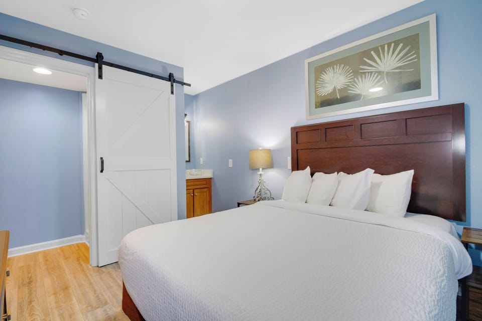 Relax in your tranquil bedroom with calming blue walls, crisp white linens, and charming barn door details that create a peaceful retreat.