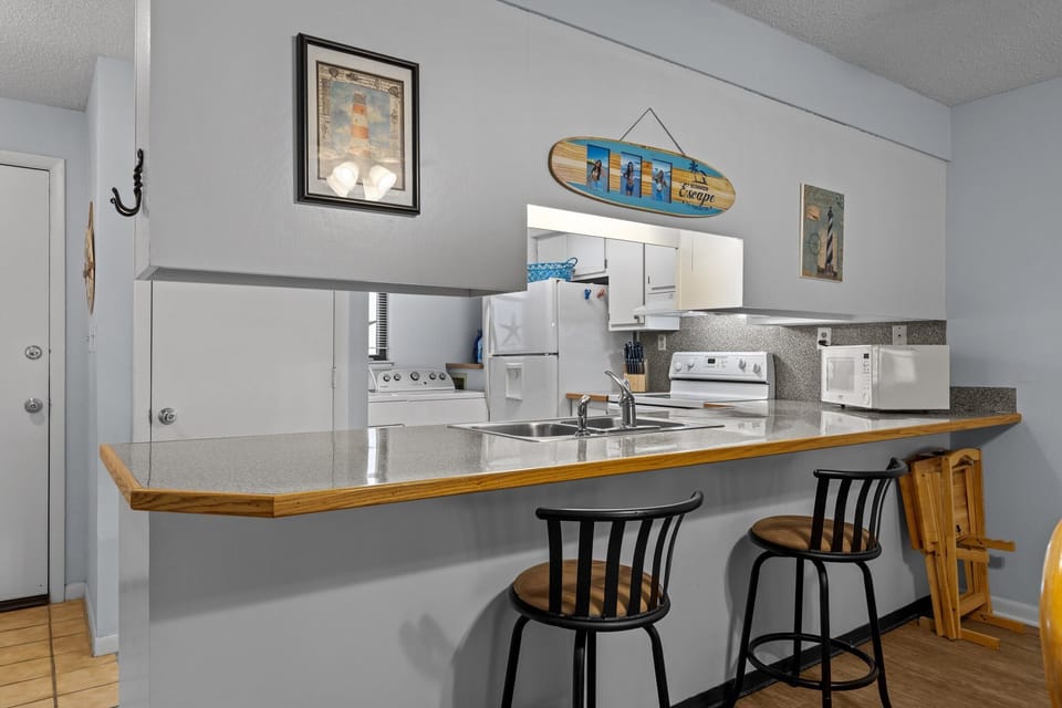 Your fully equipped kitchen features a spacious breakfast bar where you can savor morning coffee while planning beach adventures.