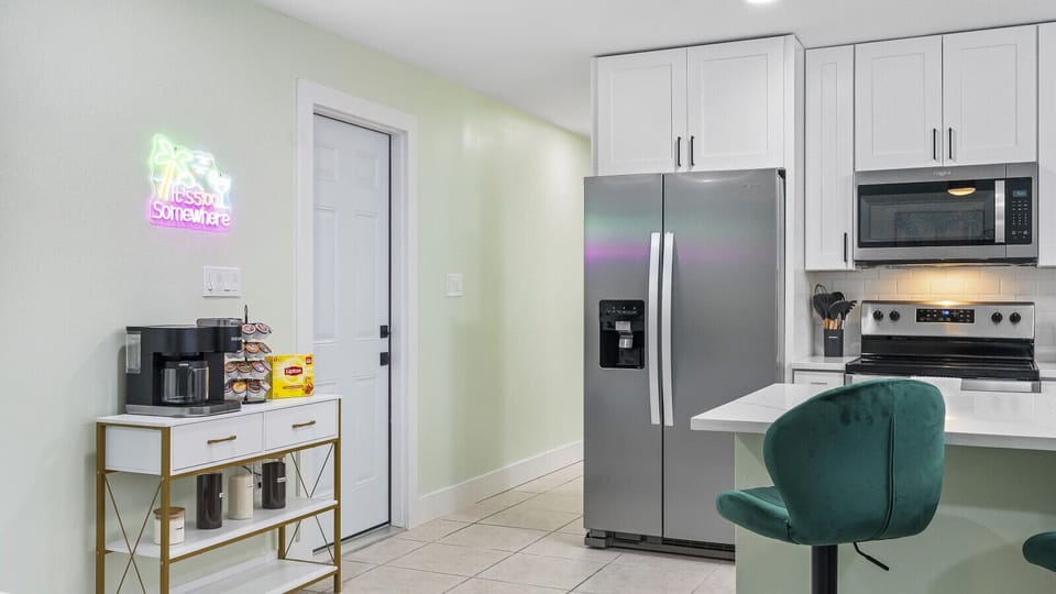 Cocoa Beach Retreat | Coffee cart, neon blossom sign, and stainless kitchen—crafted for breezy mornings and effortless coastal charm.