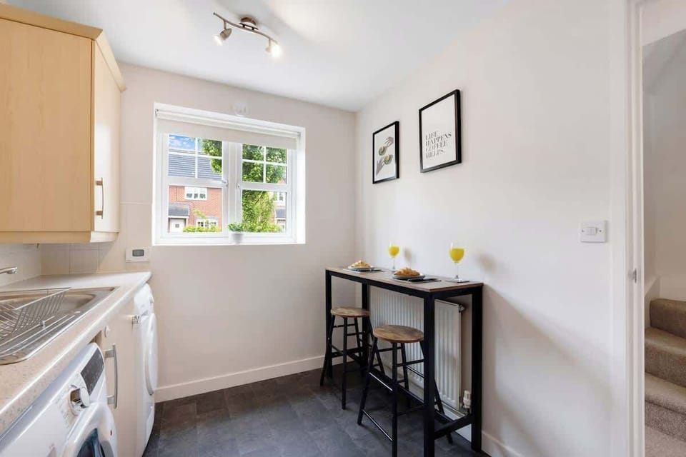 A bright and functional kitchen with an oven, fridge, and complete cookware set, enhanced by a breakfast counter designed for two guests.