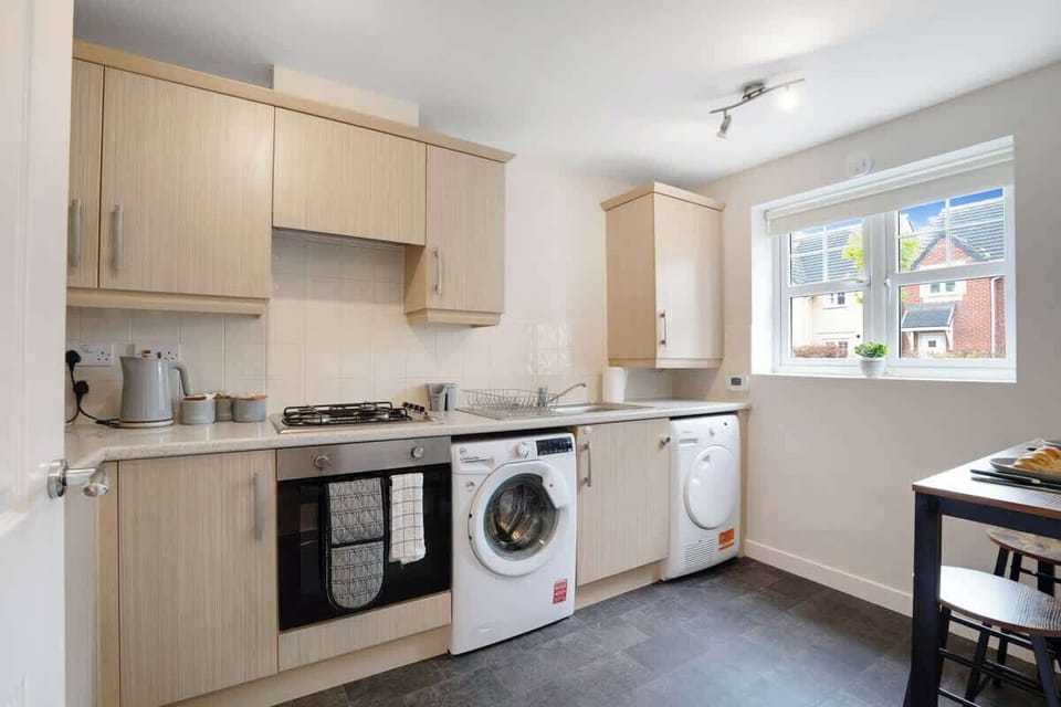 A fully equipped kitchen with all essentials, including an oven, fridge, and full cookware set, along with a breakfast counter for two perfect for casual dining.