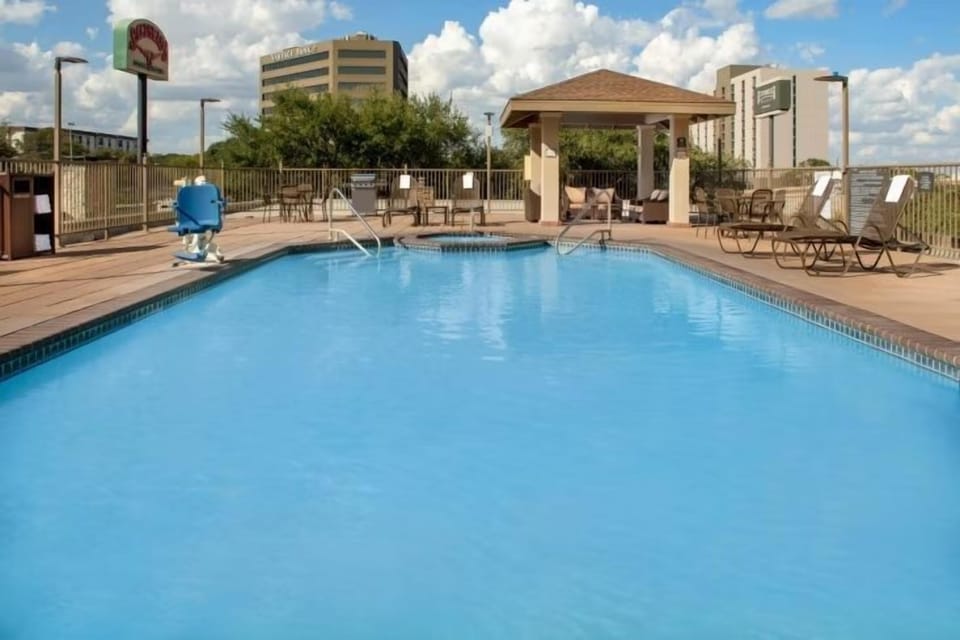 Rectangular outdoor pool with brown lounge chairs and a shaded gazebo — open year-round