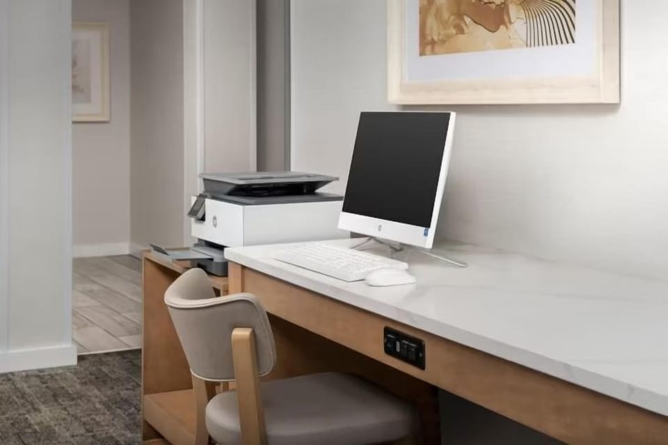 Work desk with HP printer, desktop computer, and keyboard — available in the 24-hour business center