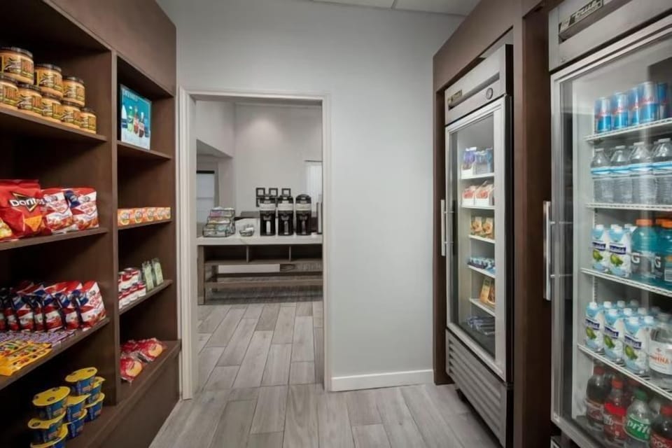 On-site pantry with snack shelves and two glass-front drinks fridges