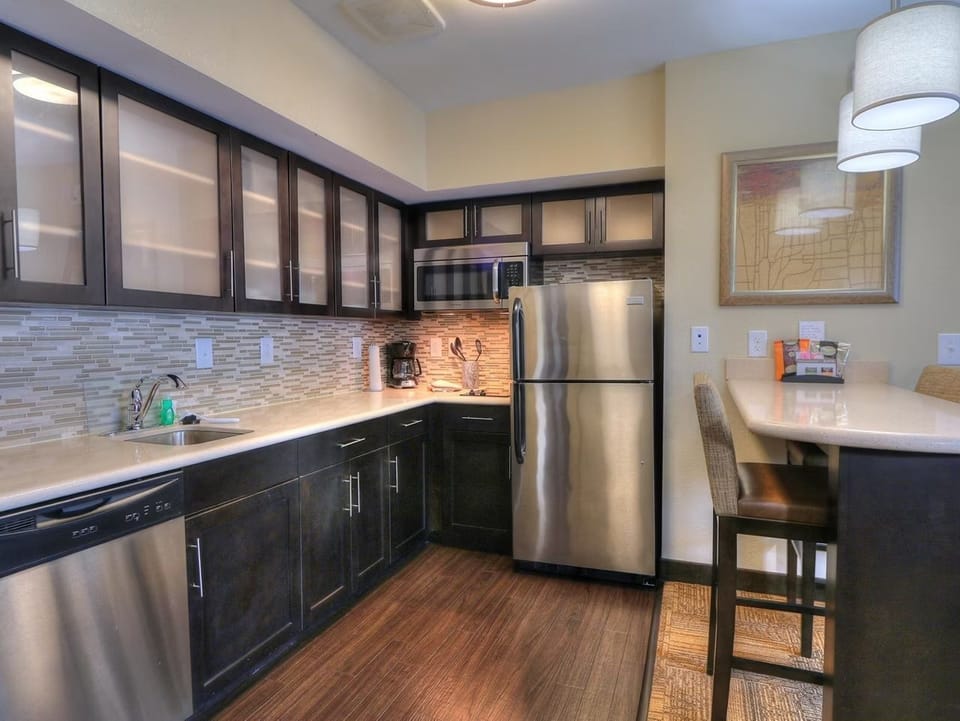 Kitchen fitted with stainless appliances — stovetop, dishwasher, microwave, and full-size refrigerator