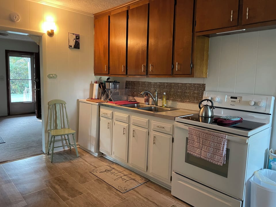 Clean and neat kitchen with complete set of glasses, dishes, pots, pans, etc.