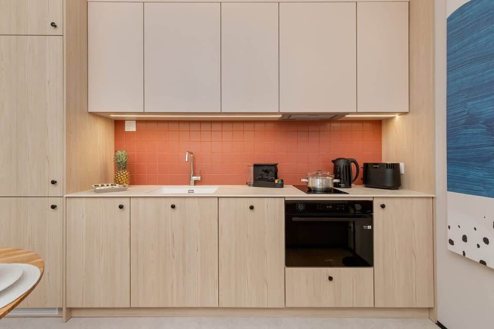Modern kitchenette in light colors, well-equipped with essential cooking appliances.