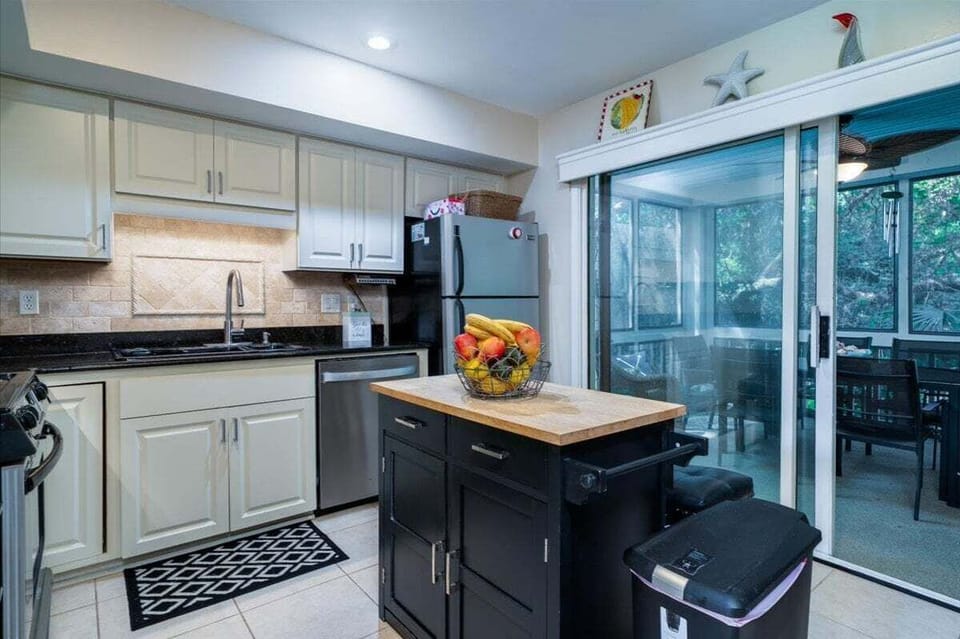 A center island has stools.  Sliding door off the kitchen leads out to the screen porch