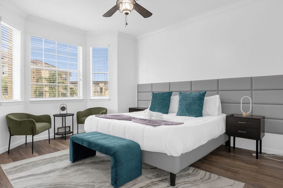 Bright king bedroom with bay windows, seating area, and stylish modern touches