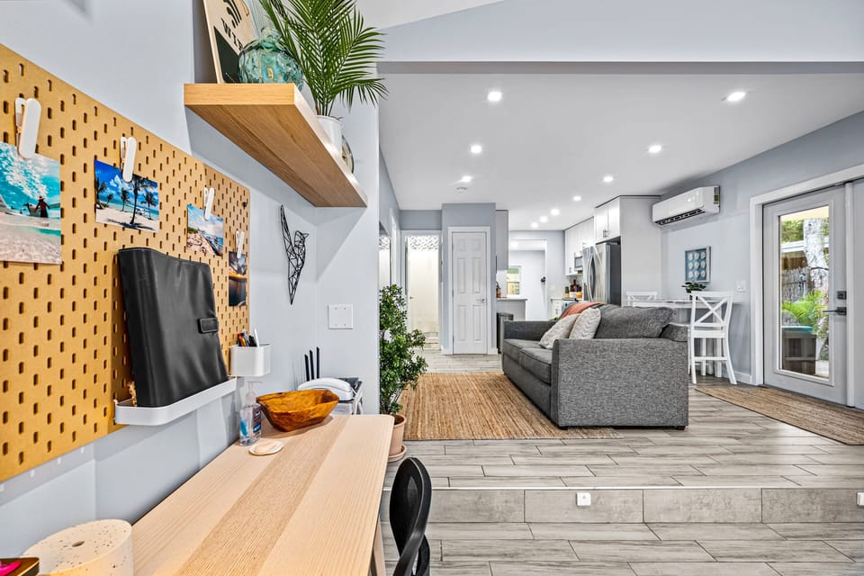 The workspace has a desk, a pegboard wall and a view into the living room.