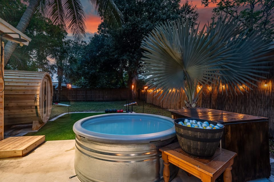 The backyard has a cold plunge tub next to the barrel sauna.
