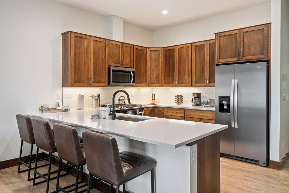 - Kitchen with wood cabinetry and polished counters   - Bar seating and open flow into dining area nearby   - Modern appliances make cooking simple and enjoyable