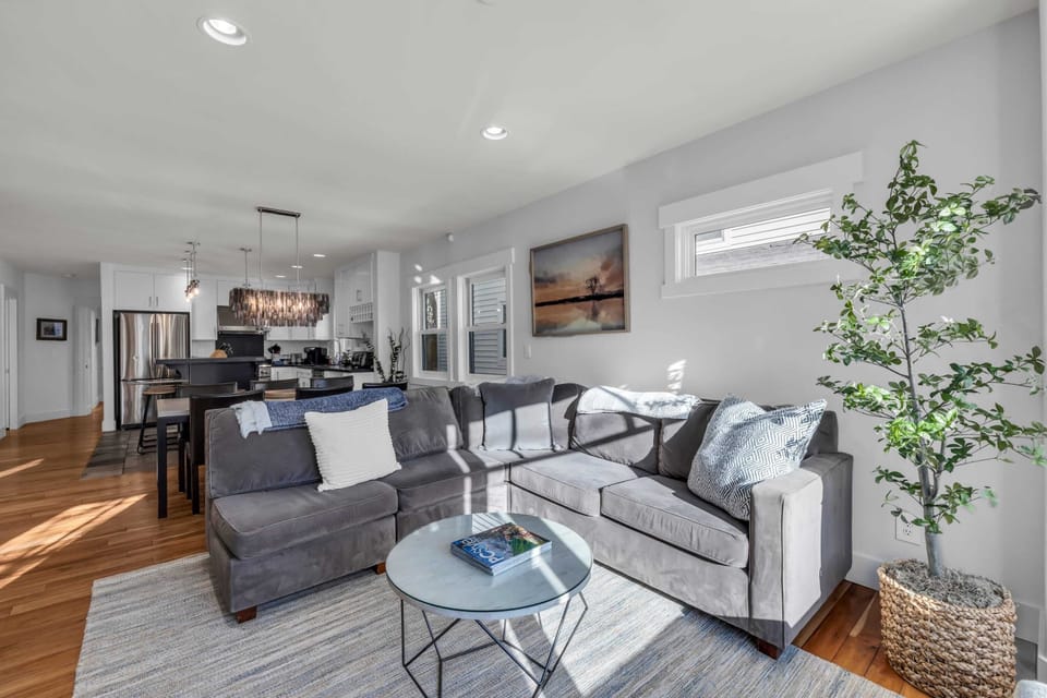 Living Room 1: L-shaped couch, Samsung TV, open layout to kitchen and dining room, main floor
