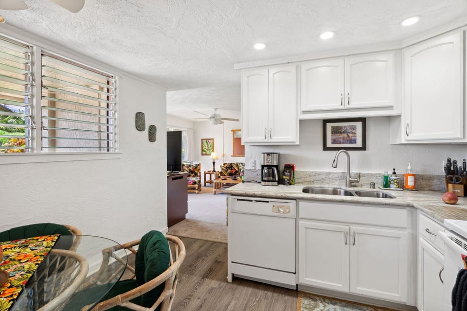 Fully equipped white kitchen with dishwasher, plenty of counter space, and seating for four