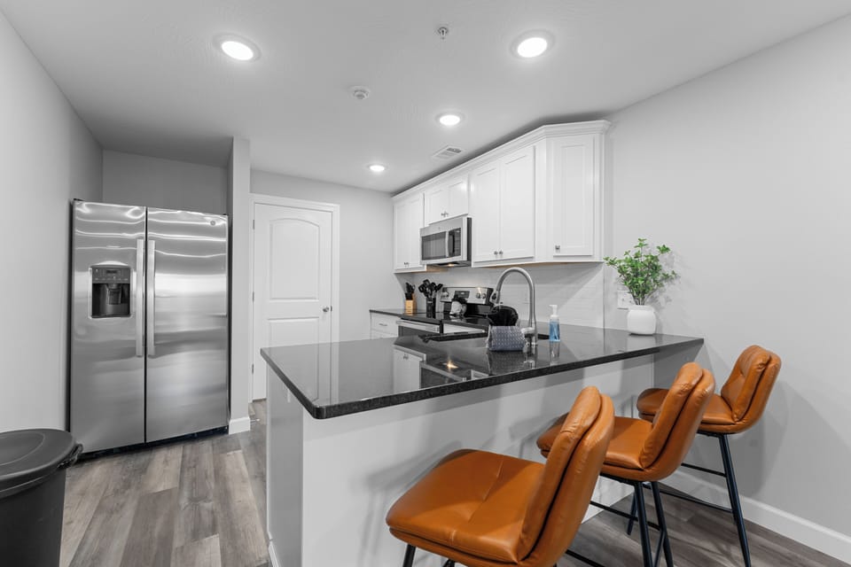 An inviting kitchen featuring a sleek countertop with three modern bar stools.