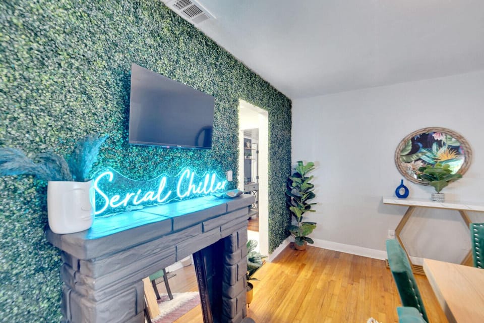 A vibrant, funky dining room with unique wallpaper, a lively grass wall, and a fun lighted sign
