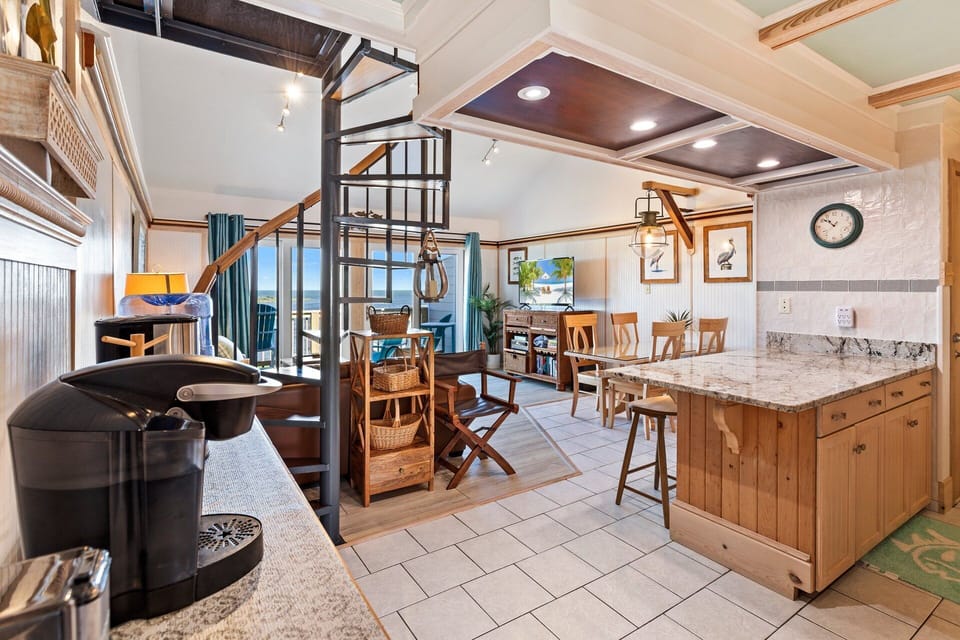 The open-concept Main Level boasts a cozy Living Area with high ceilings, a large Flat Screen TV, and a wall with windows and glass sliders overlooking the Pamlico Sound!