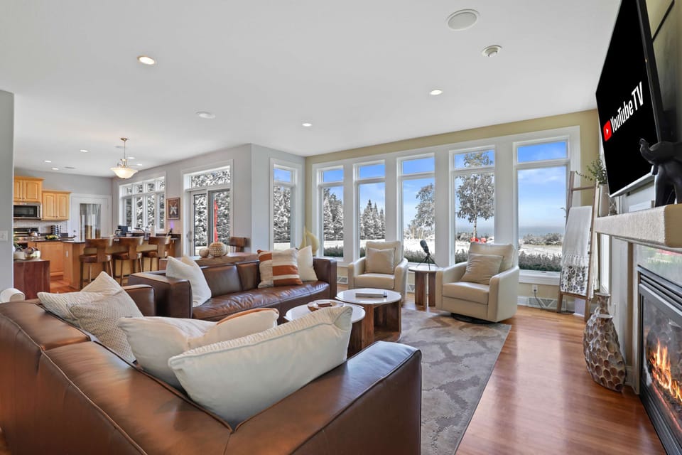 Open concept main level boasting floor to ceiling windows along the lakeside, luxury furniture and gas fire place.