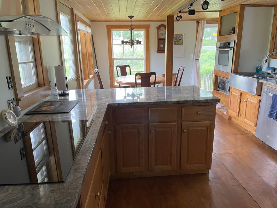 Kitchen with induction stove top looking toward oak table and outdoor open space