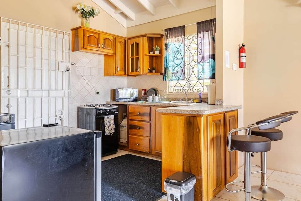 Fully equipped kitchen, featuring warm wood cabinetry, modern appliances and breakfast-bar seating