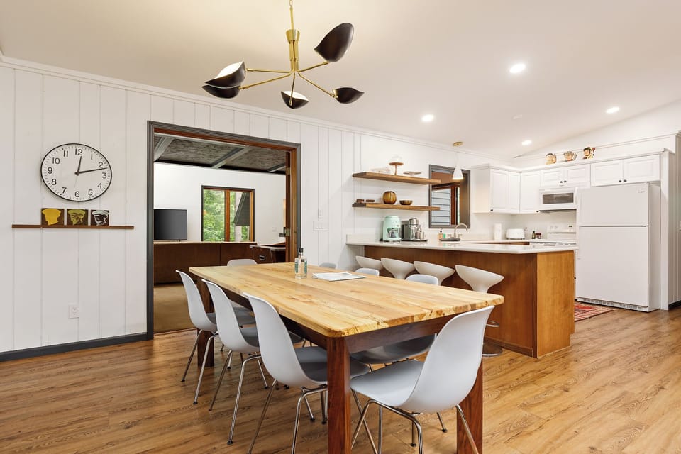 Bright kitchen & dining area w/ large wood table for 8, open shelving & plenty of space to cook together.
