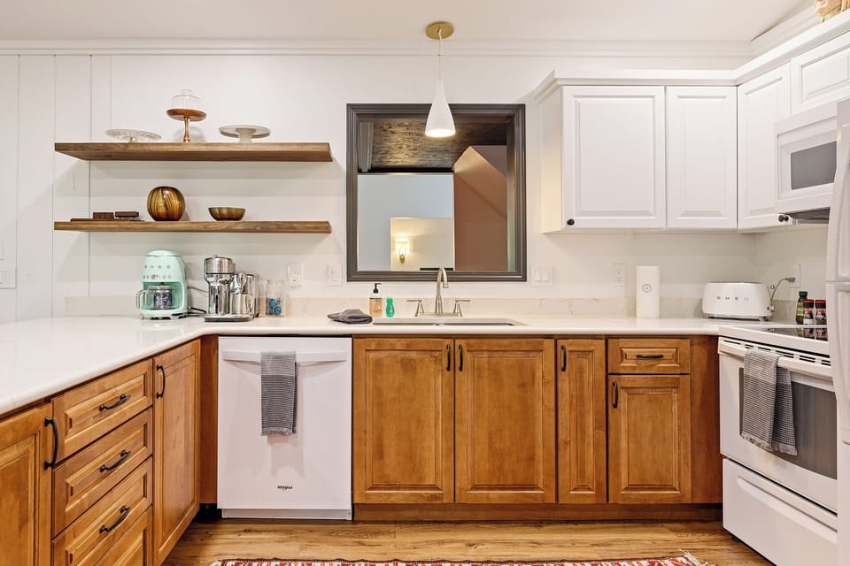 Bright kitchen w/ warm wood cabinetry, open shelving & everything set for easy home cooking.