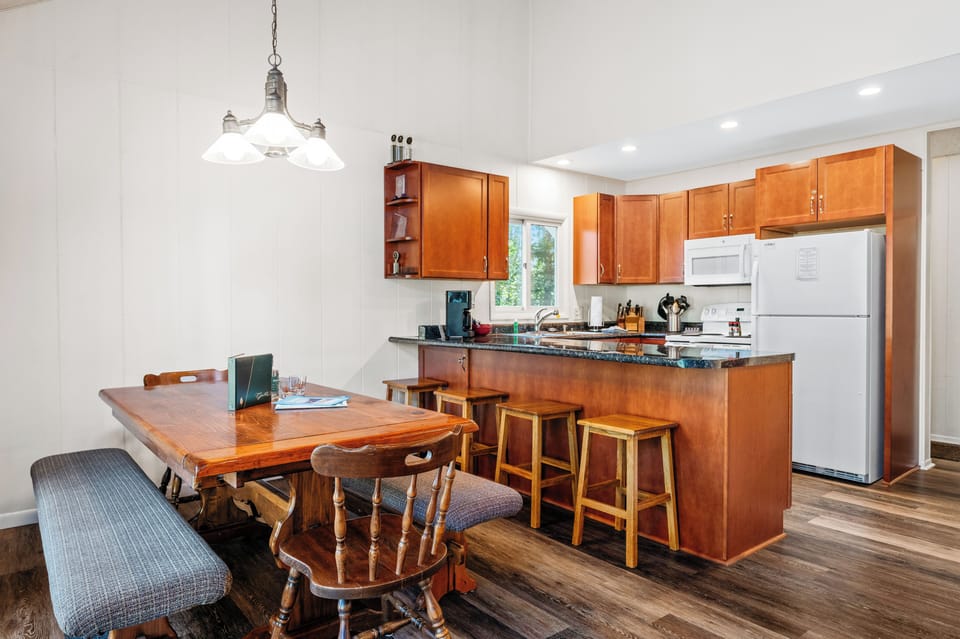 Open-concept kitchen & dining area w/ bar seating, granite counters & space for shared meals.
