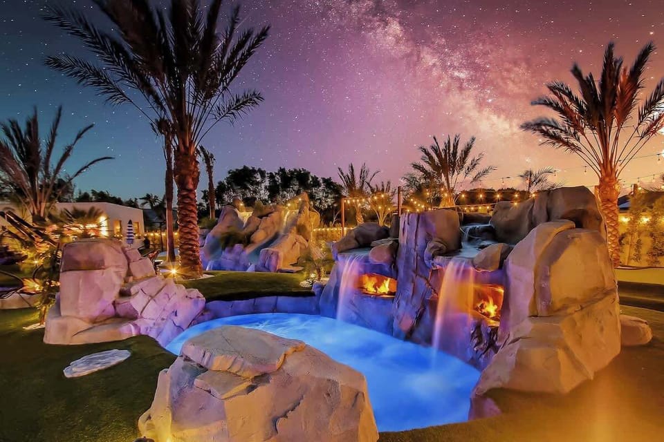 Stunning twilight shot highlights the cascading waterfalls and illuminated pool features.