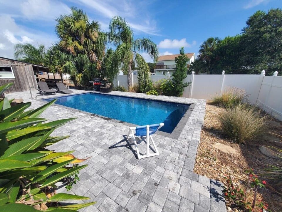Sunny private pool with spacious patio and lush landscaping.