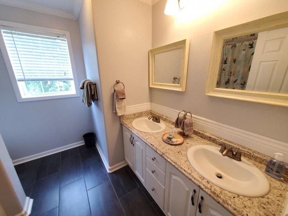 Elegant bathroom with dual sinks and a serene view from the window.