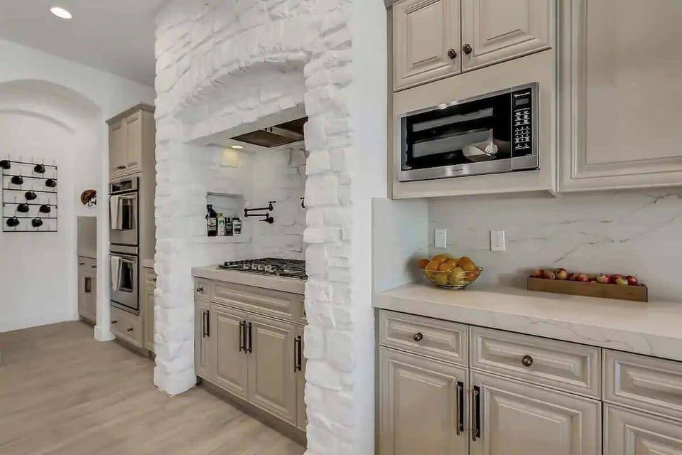 Timeless charm meets convenience with this stone arch leading to a spacious pantry and beautifully organized kitchen essentials.