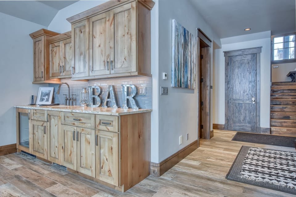 Lower level living room with gas fireplace, mounted TV, and wet bar