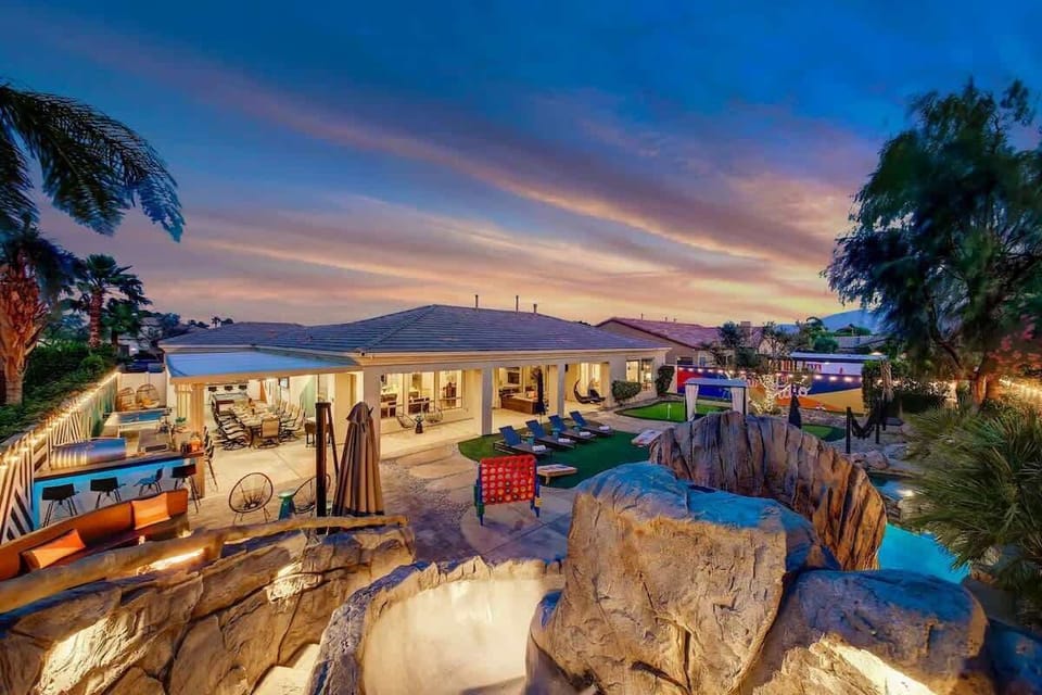 Dive into luxury with a sprawling pool surrounded by resort-style loungers and a dramatic rock waterfall feature.