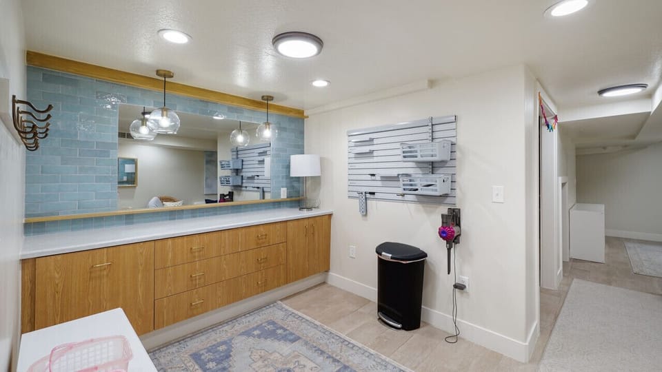 Inviting and functional: an open space featuring expansive wooden cabinets, a chic mirror, practical hooks, and a convenient trash bin for a clutter-free environment.