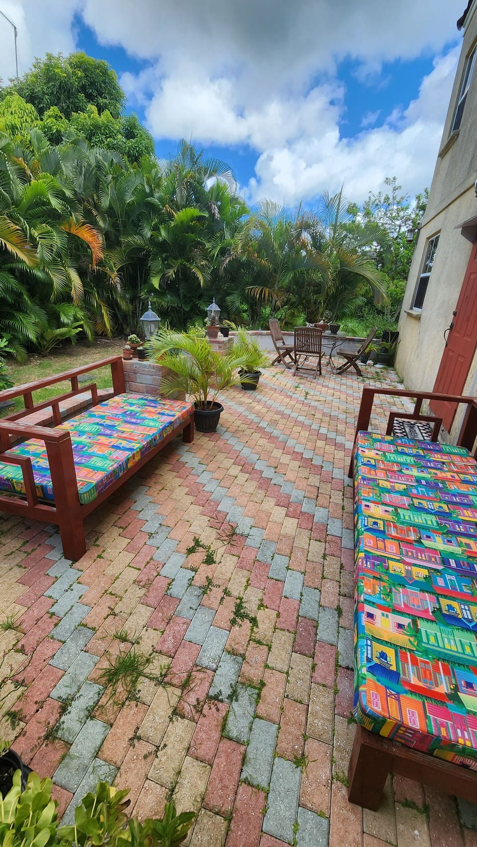 Back patio with sofas, breakfast table, fire pit & lush palm trees overhead.
