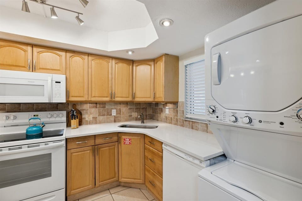 Modern kitchen with warm wood cabinetry and a convenient washer and dryer