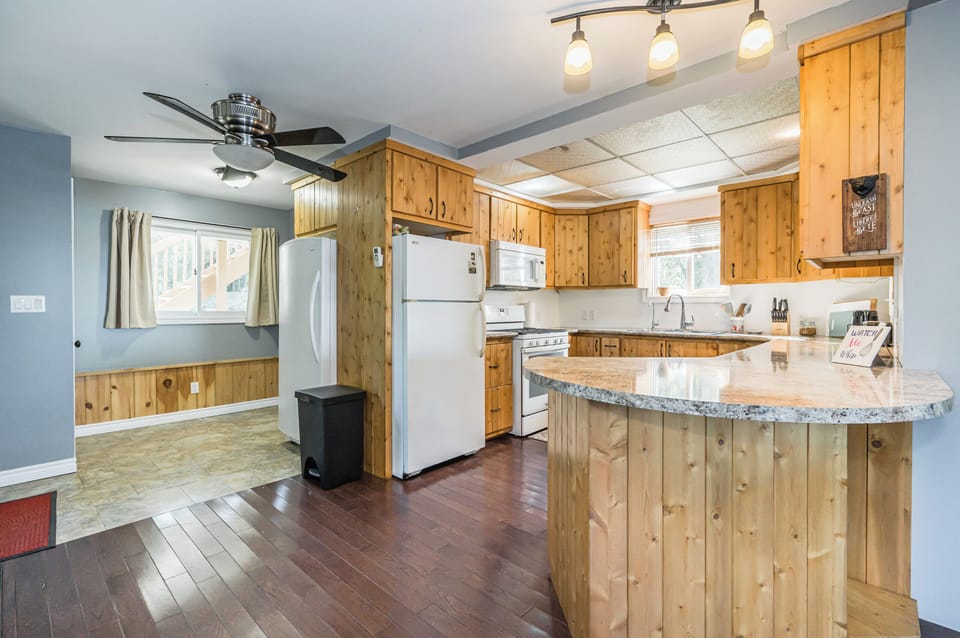 Enjoy cooking in this spacious kitchen with rustic wood-paneled cabinets, a stylish ceiling fan, and ample natural light – perfect for family meals.