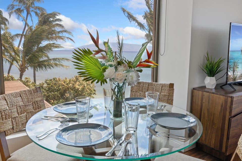 Gather around the elegant glass dining table and enjoy sweeping views of the ocean and palm trees for a tropical dining experience.