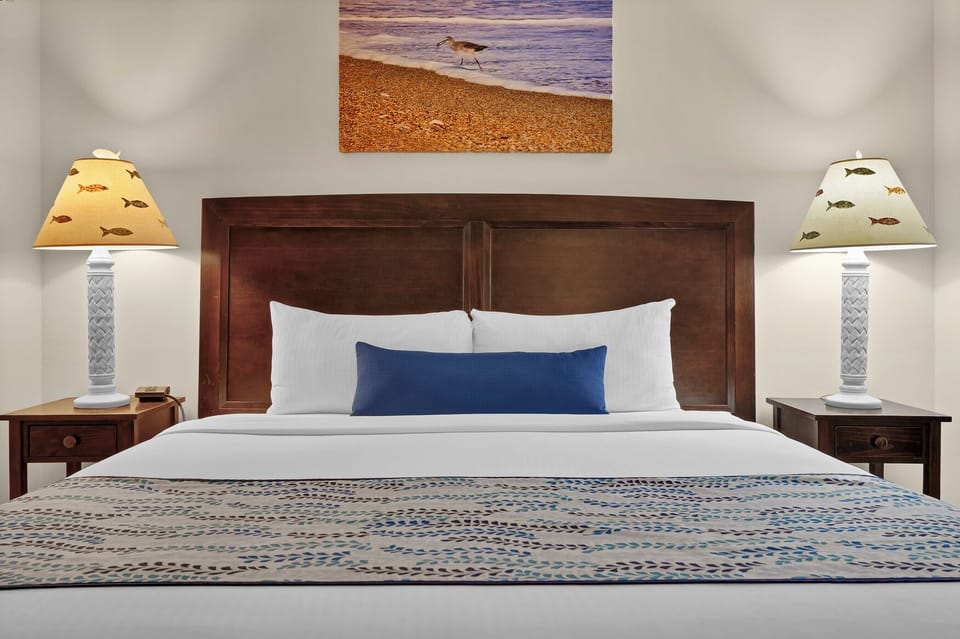 Unwind in your comfortable bedroom featuring coastal-themed decor, crisp linens, and charming fish-motif lamps that create a relaxing seaside atmosphere.